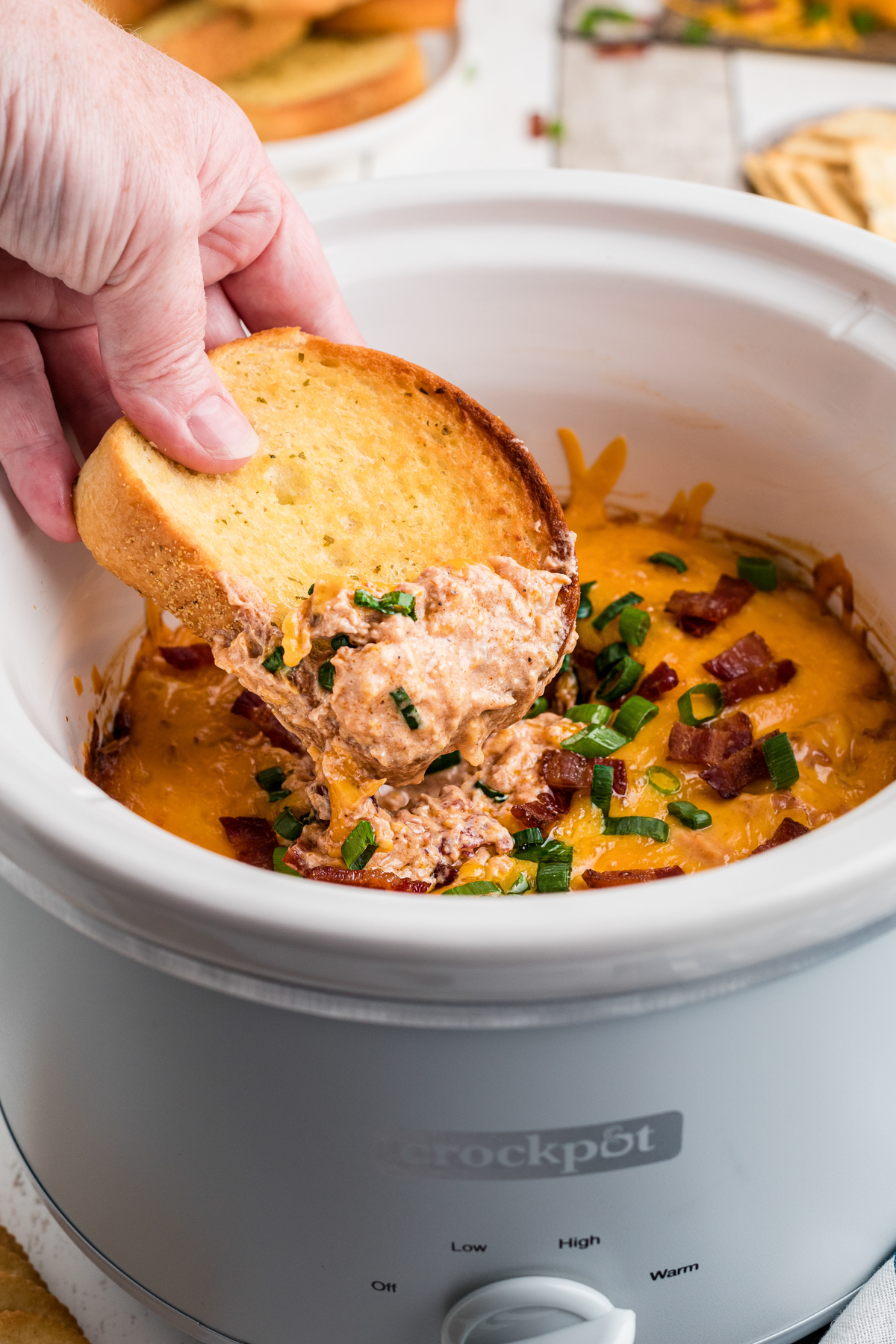 dipping garlic bread into crockpot barbecue chicken dip.