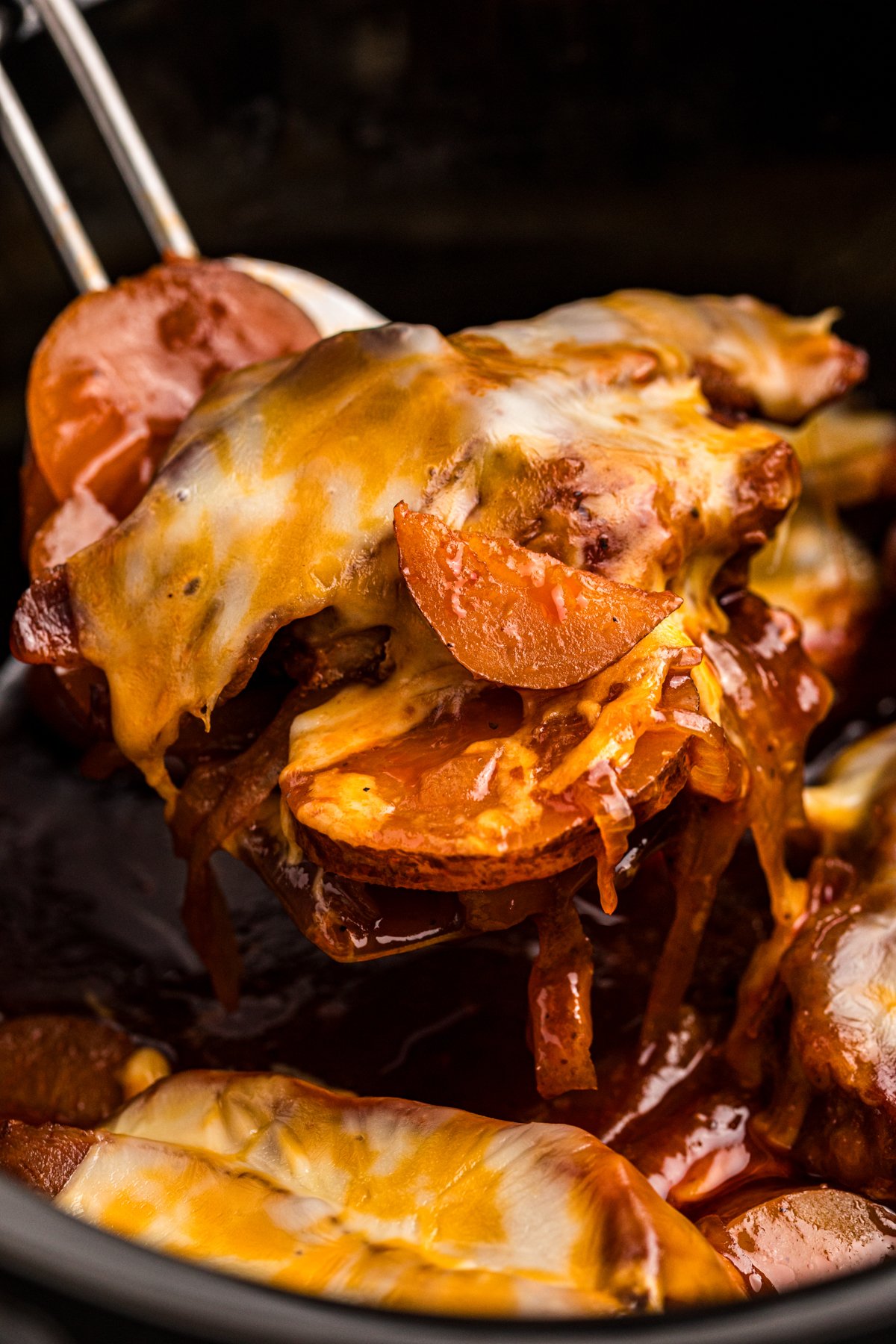 close-up of scoop of slow cooker barbecue pork chops and potatoes.