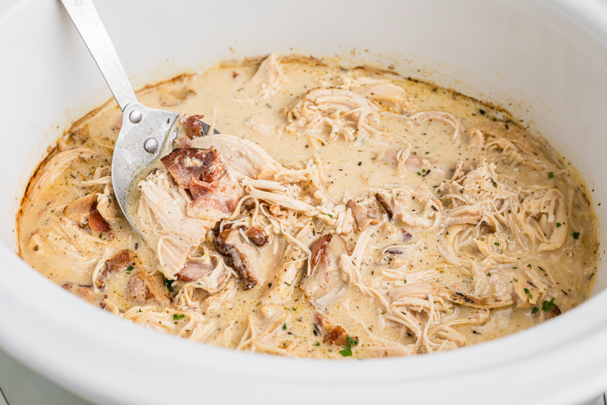 chicken in a creamy bacon gravy with a metal spoon in it.