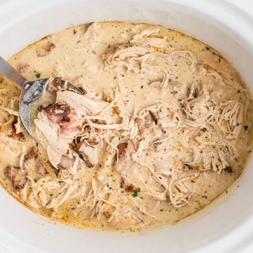 chicken with bacon gravy in a slow cooker on a spoon.