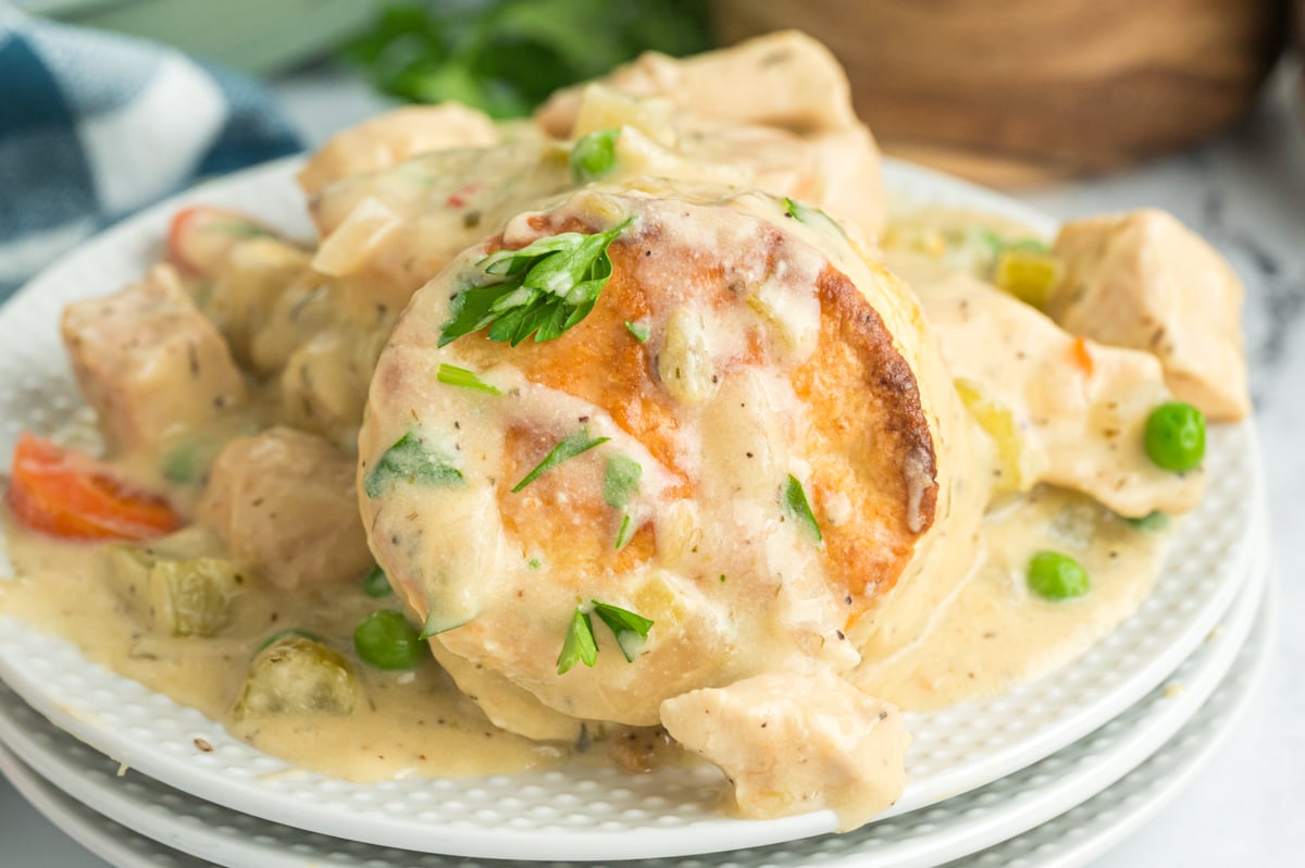 A serving of crockpot chicken pot pie on a stack of white plates.