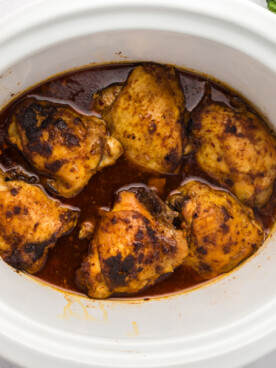 overhead of chicken thighs in a slow cooker.