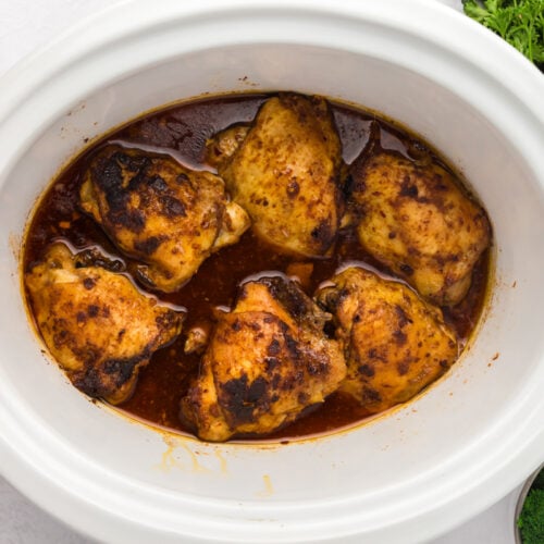 overhead of chicken thighs in a slow cooker.