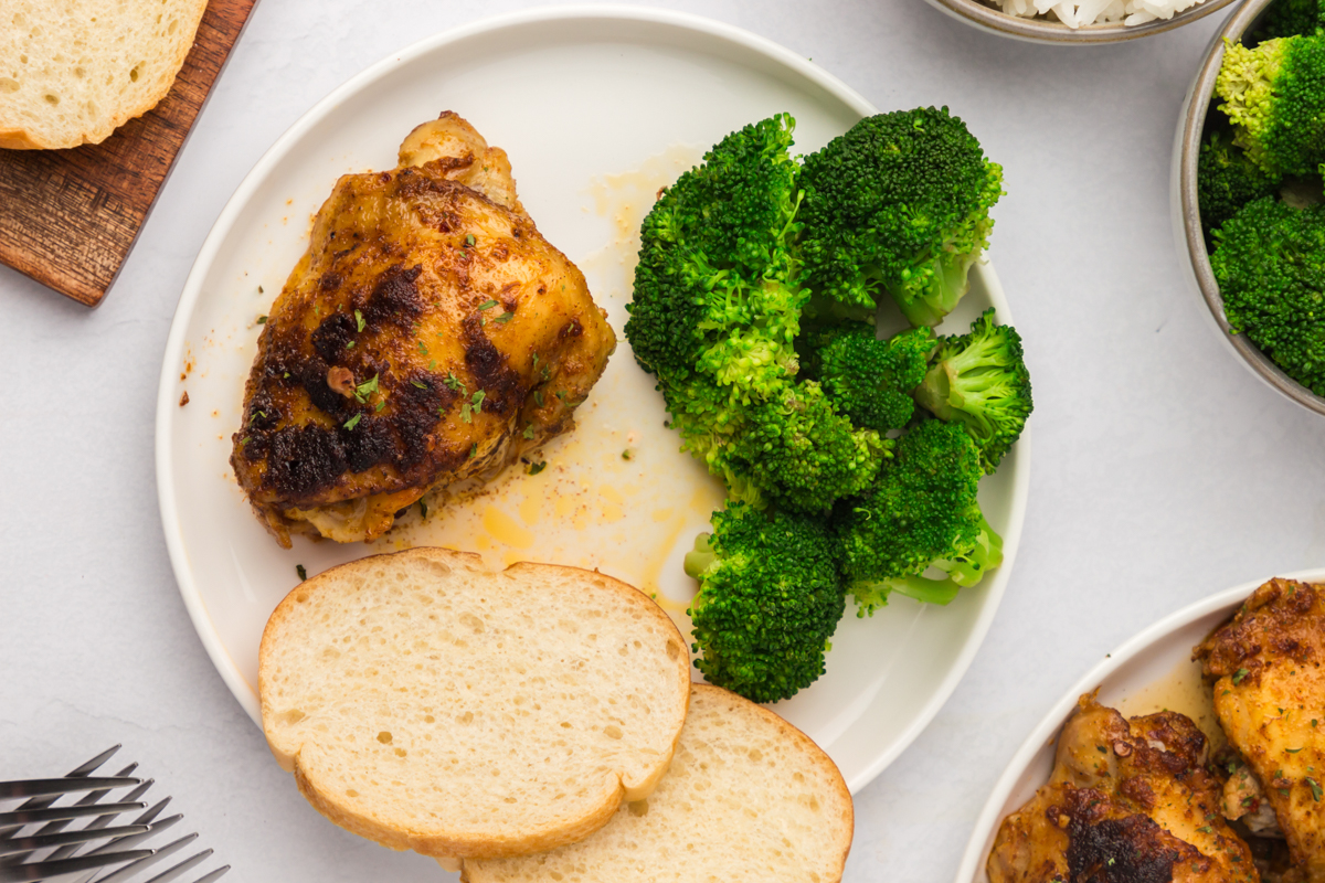 overhead shot of a serving of slow cooker chicken thighs on a white plate.