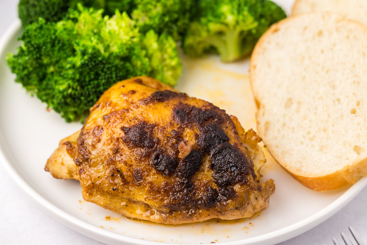 close-up of serving of slow cooker chicken thighs on a white plate.