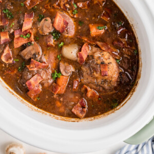 overhead shot of coq au vin in a white slow cooker.