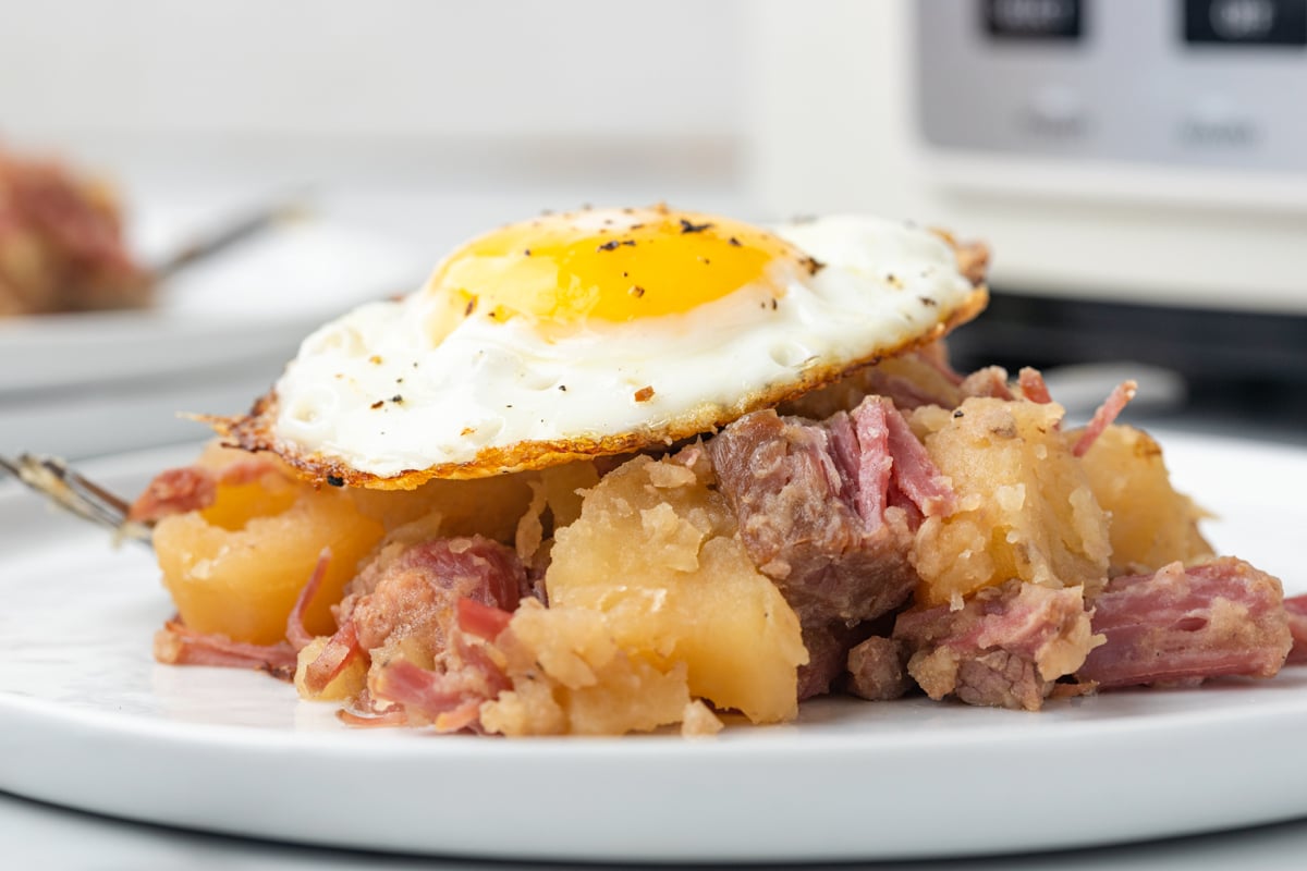 Corned beef and cabbage on a plate with a fried egg on top.