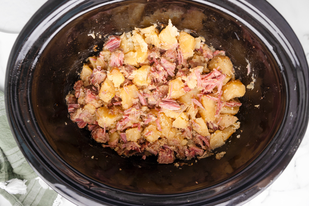 shredded corned beef and potatoes in a slow cooker.