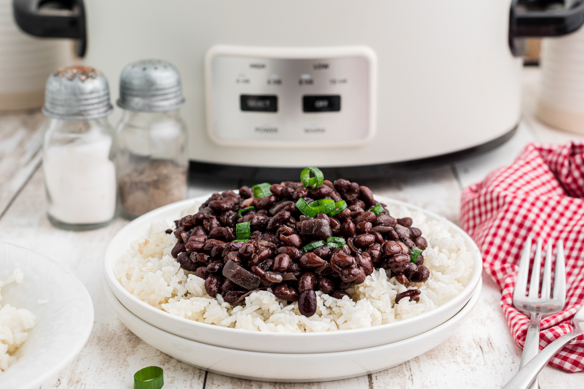 black beans over rice on a plate in front of a slow cooker.