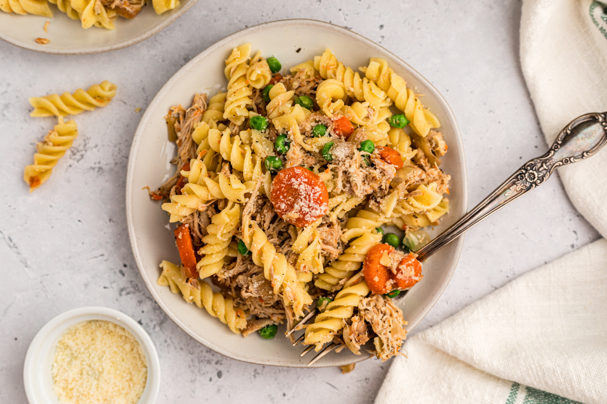 overhead of slow cooker garlic butter chicken and pasta on a white plate.