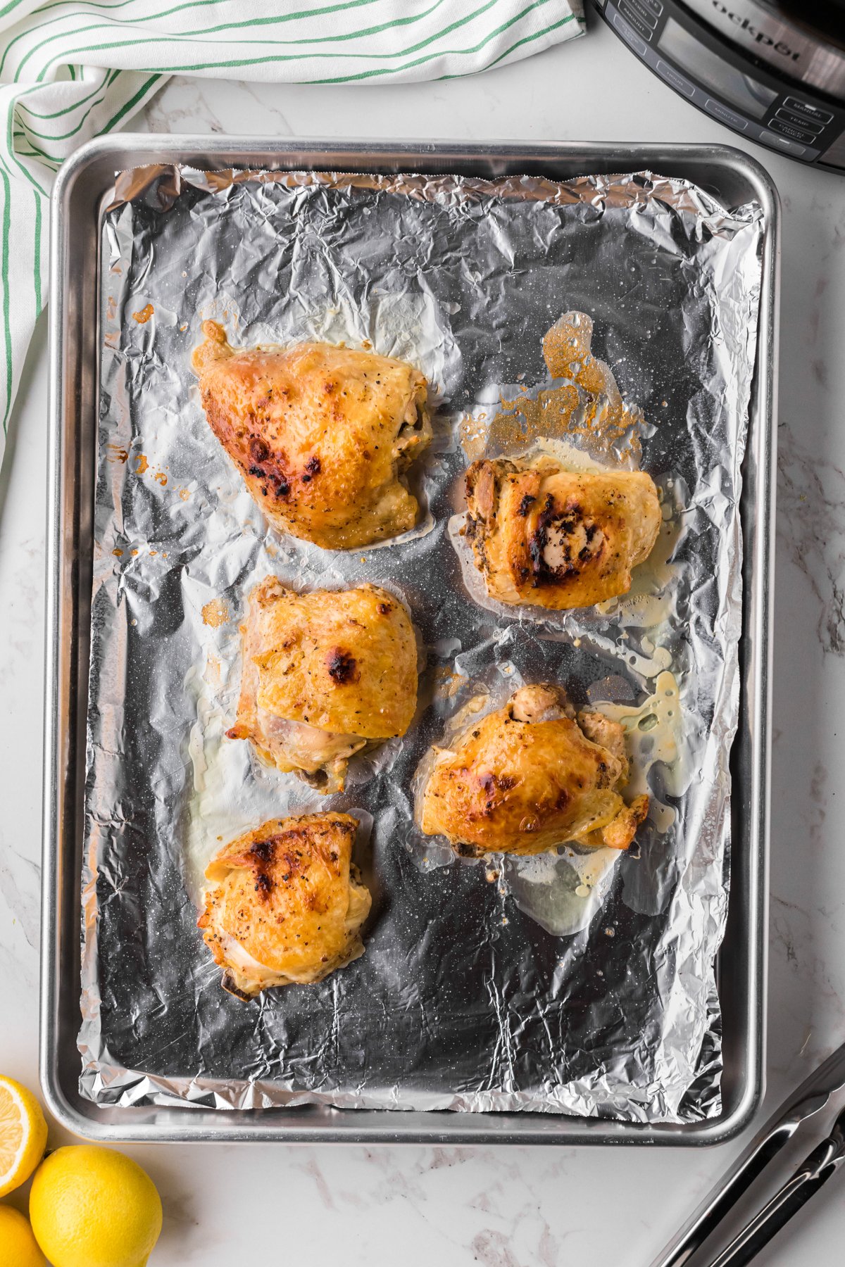 Chicken thighs being browned on a sheet pan.