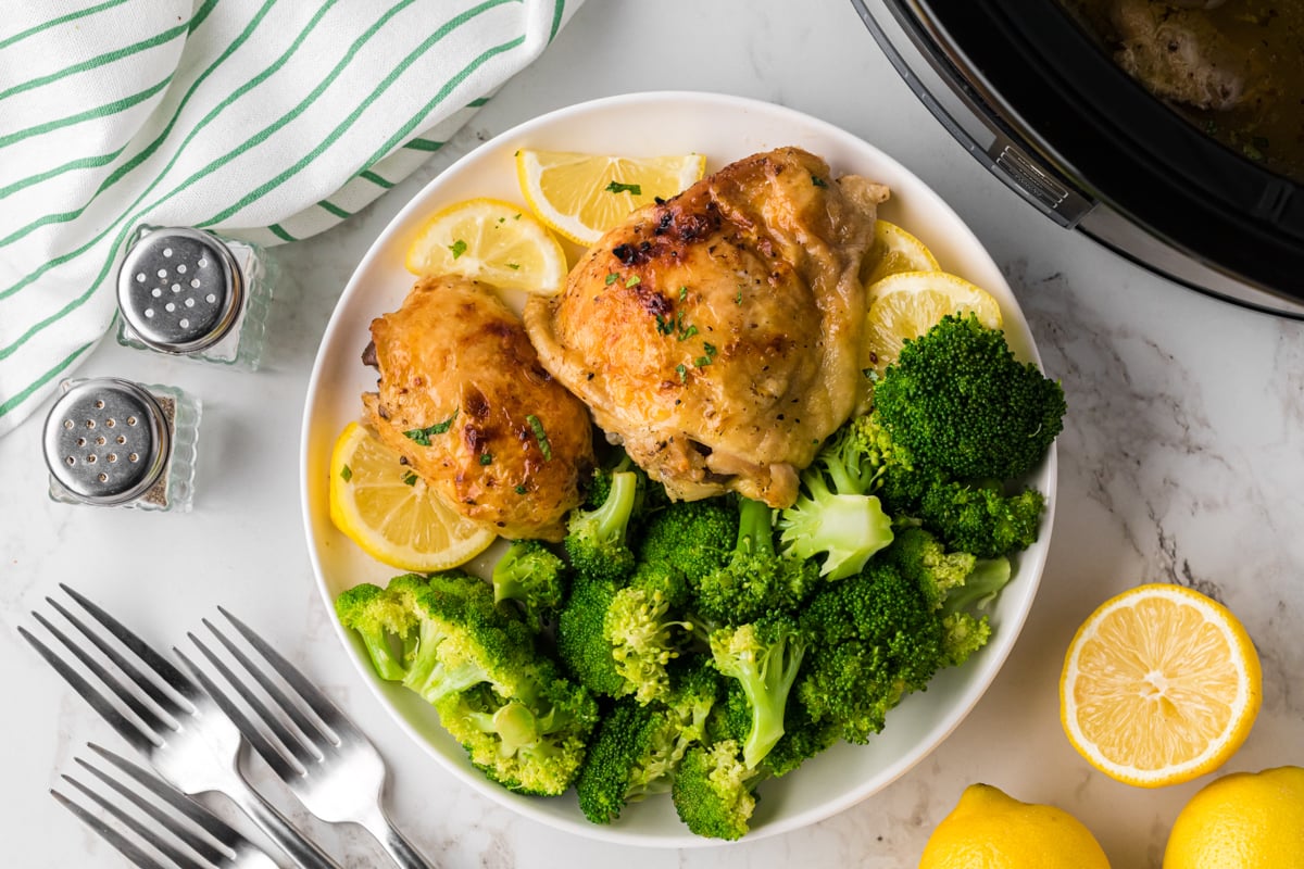 overhead of serving of crockpot lemon pepper chicken thighs on a white plate.