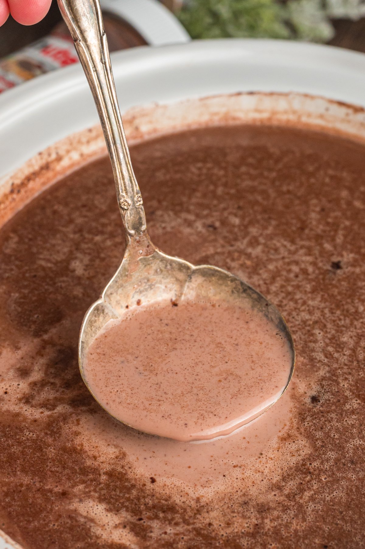 Nutella hot chocolate in a slow cooker and in a metal ladle.