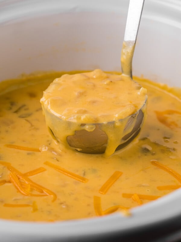 Potato cheese soup on a ladle coming from a crockpot.