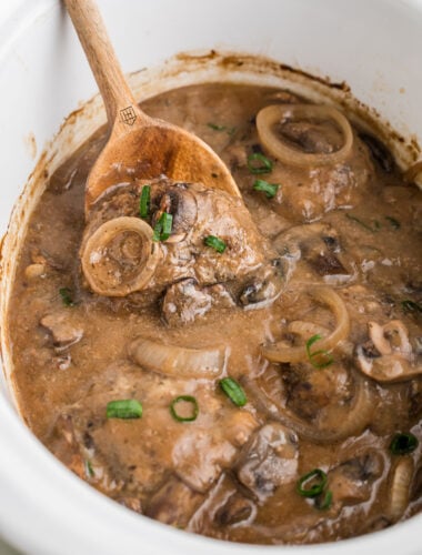 Salisbury steak patties in a slow cooker with gravy, onions and mushrooms.
