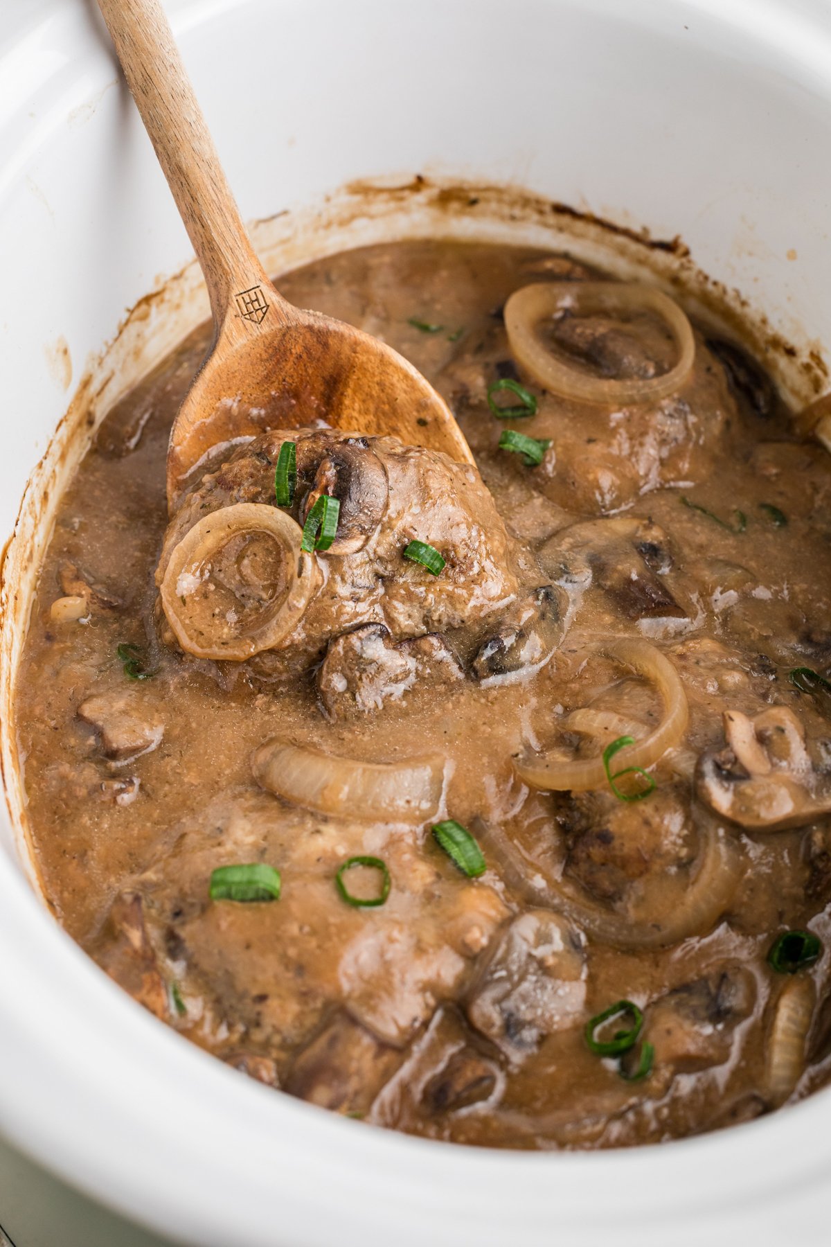 Salisbury steak patties in a slow cooker with gravy, onions and mushrooms.