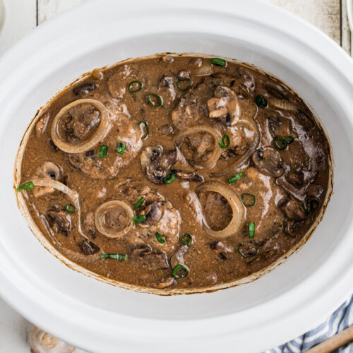 salsibury steak patties in a slow cooker with gravy and onions.