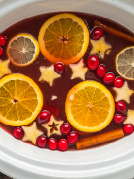 Red punch with lots of fruit in it in a slow cooker.