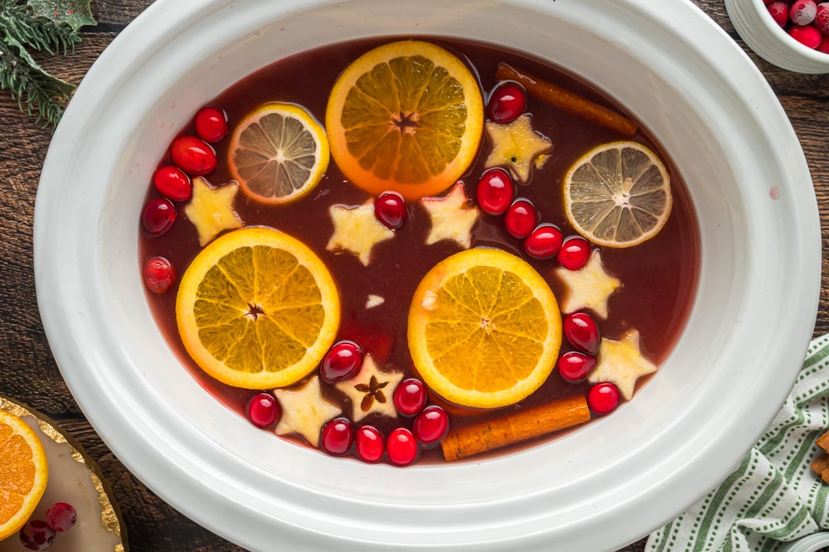 Red punch with lots of fruit in it in a slow cooker.