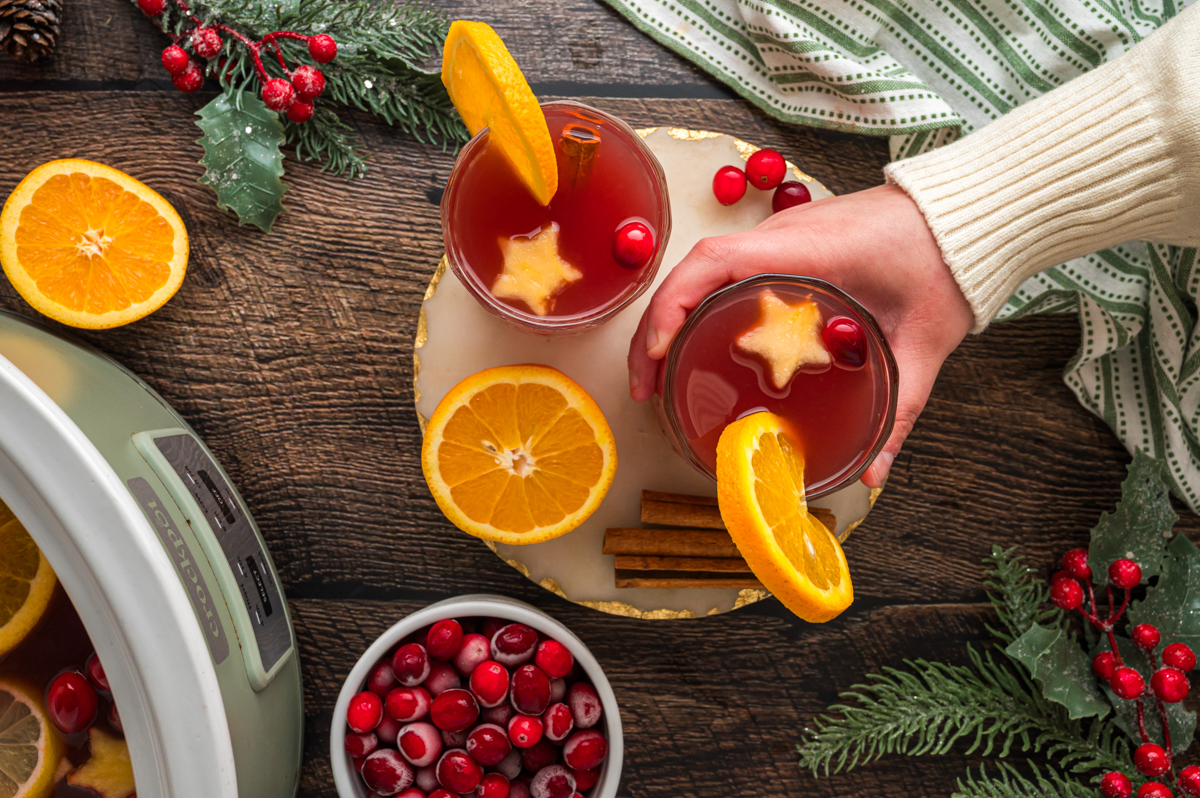 A hand grabbing a cup of warm christmas punch.
