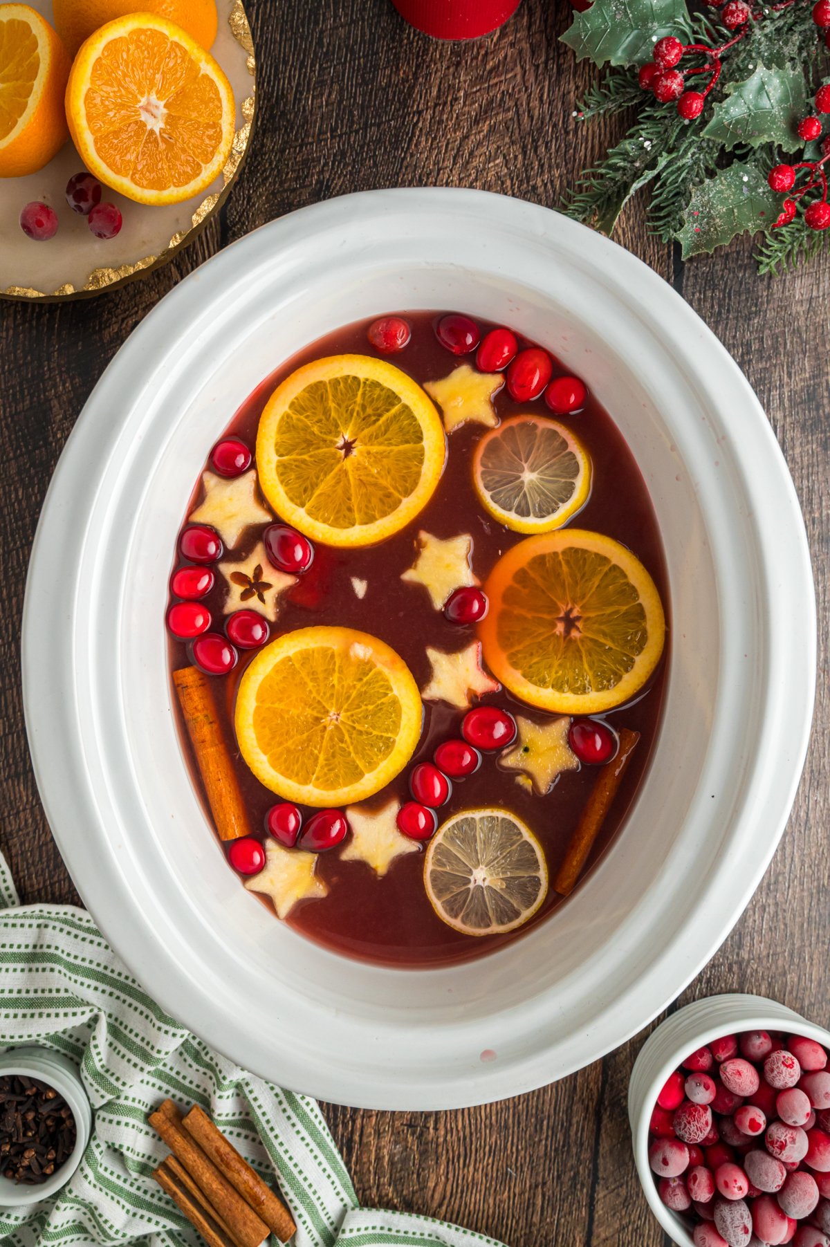 Slow cooker full of warm christmas punch with fruit floating in it.