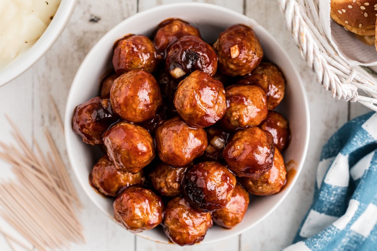 close-up overhead of slow cooker bbq meatballs in a white bowl.