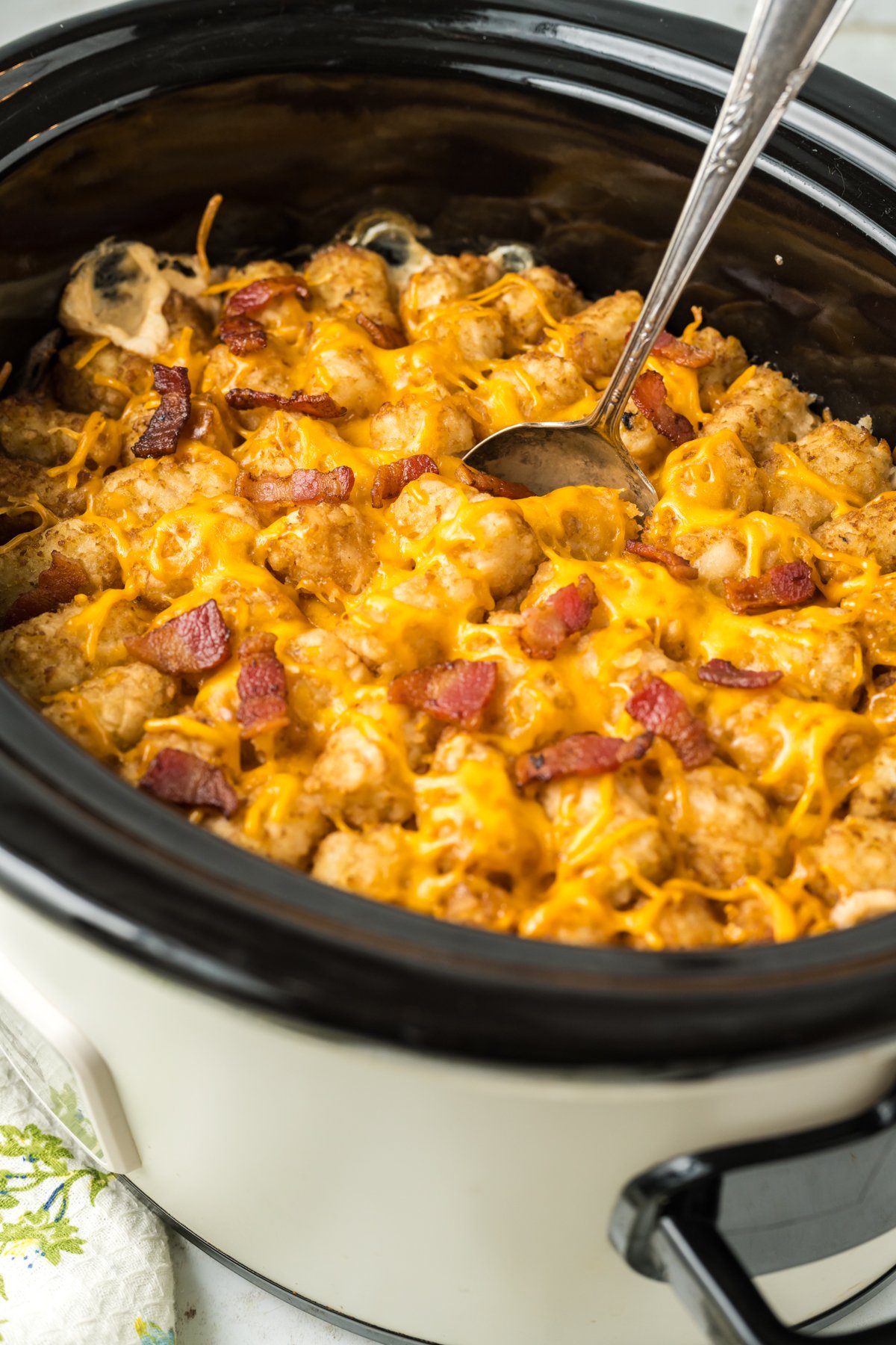 tater tot casserole with bacon on top in a slow cooker.