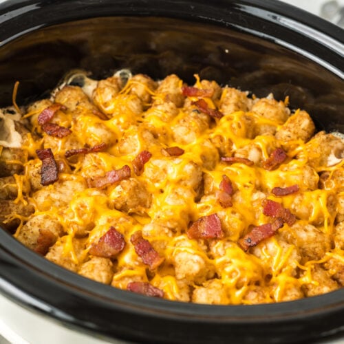 Cooked bacon cheese burger tater tot casserole in a slow cooker.