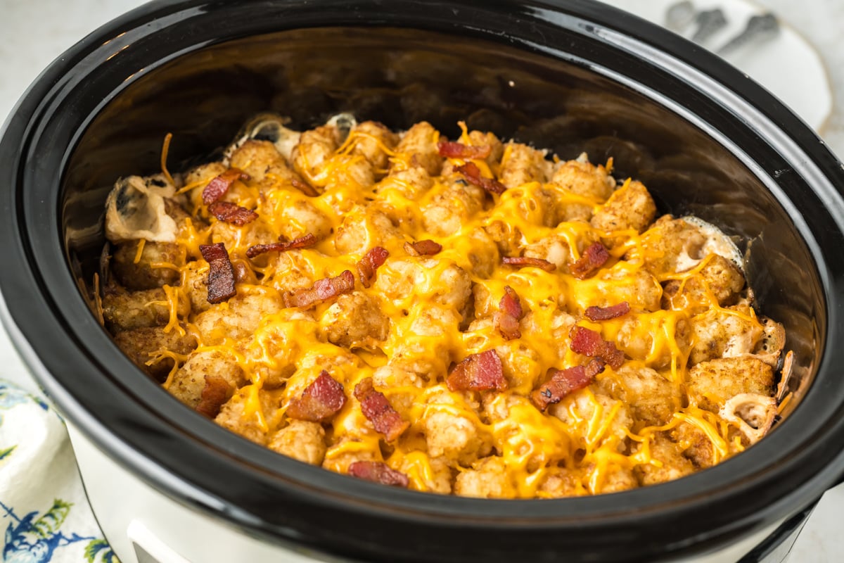 Cooked bacon cheese burger tater tot casserole in a slow cooker.