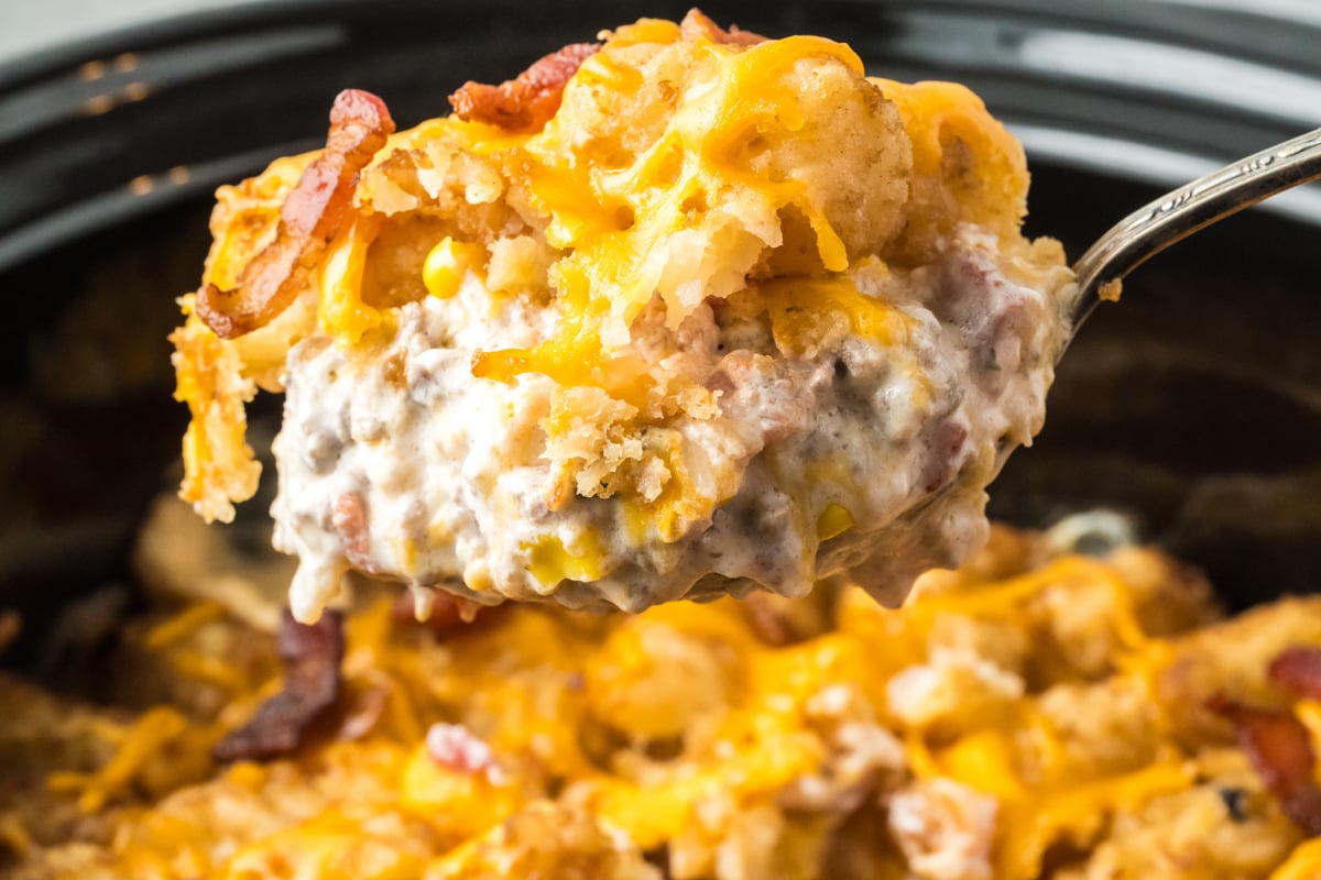 Scoop of bacon cheeseburger tater tot casserole coming from crockpot.