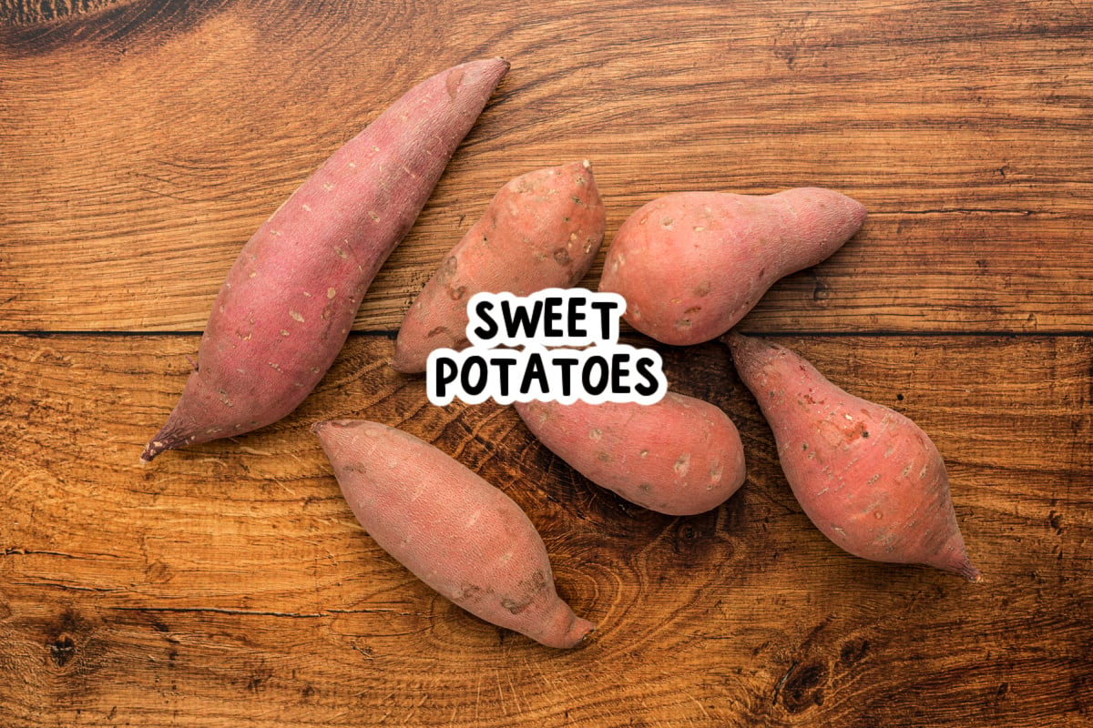 uncooked sweet potatoes on a wooden surface.