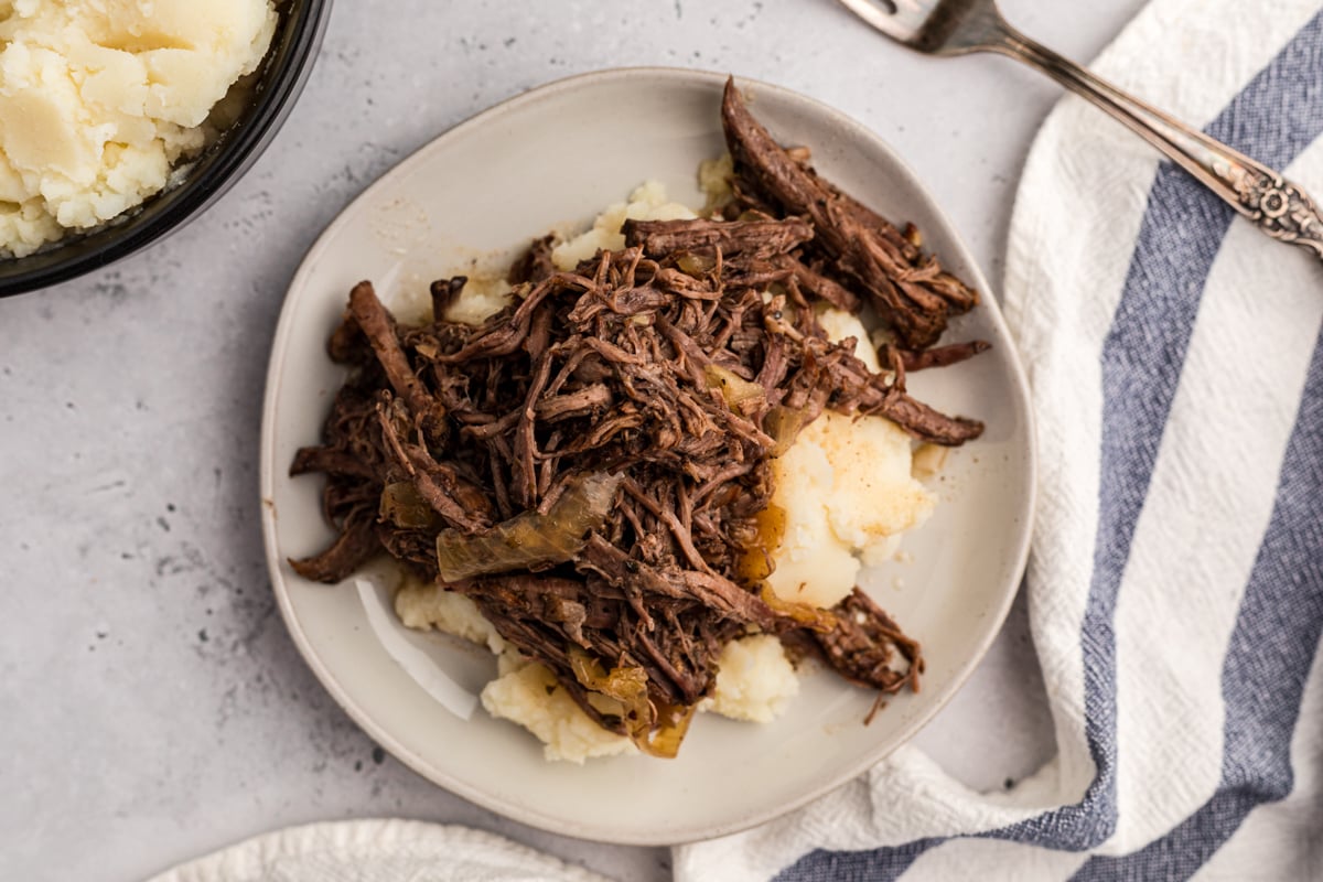 overhead of serving of slow cooker balsamic beef on a white plate.