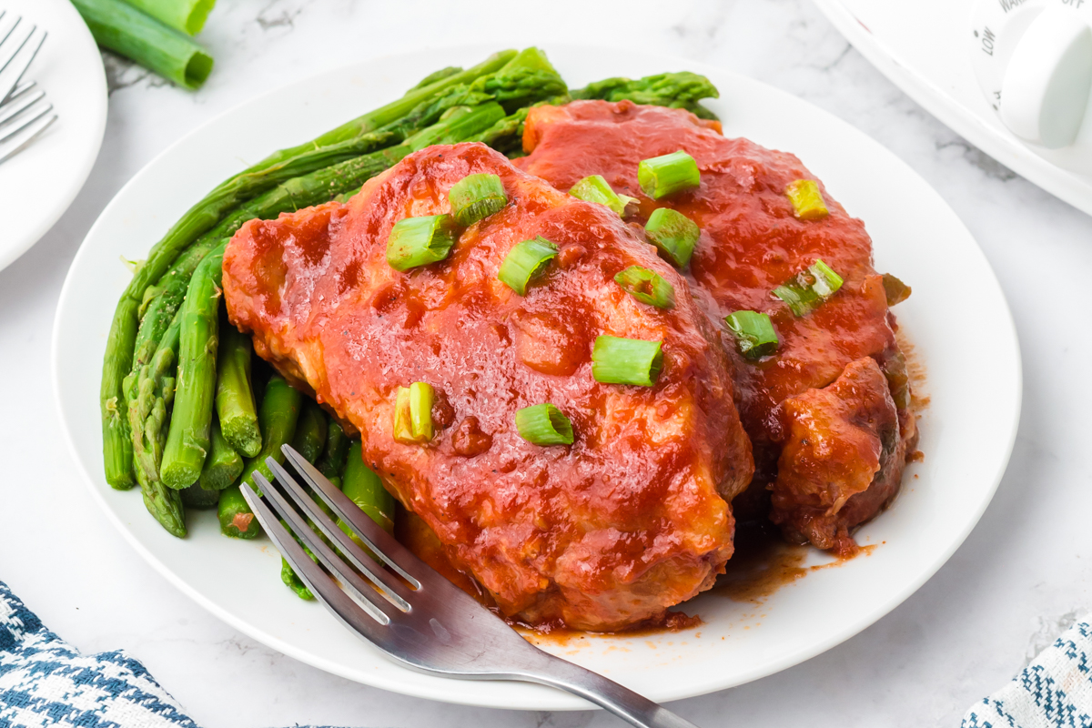 two slow cooker bbq pork chops on a white plate.