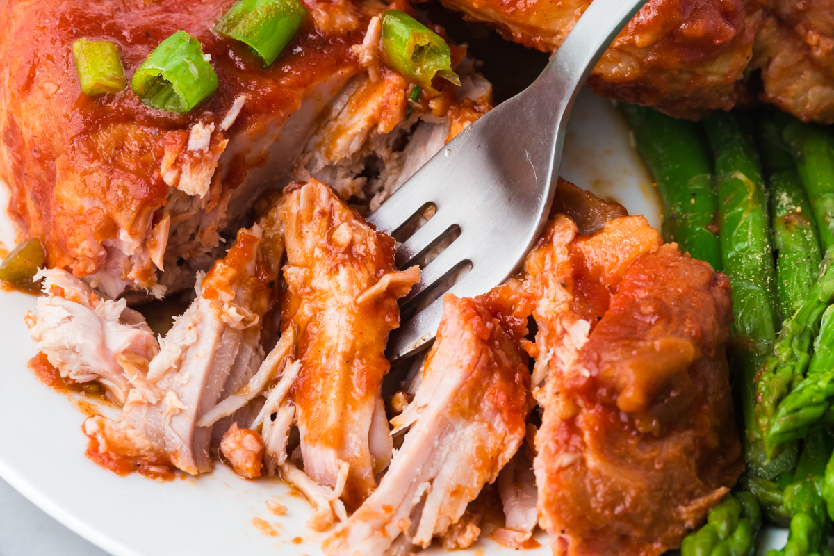 fork cutting into serving of slow cooker bbq pork chops.