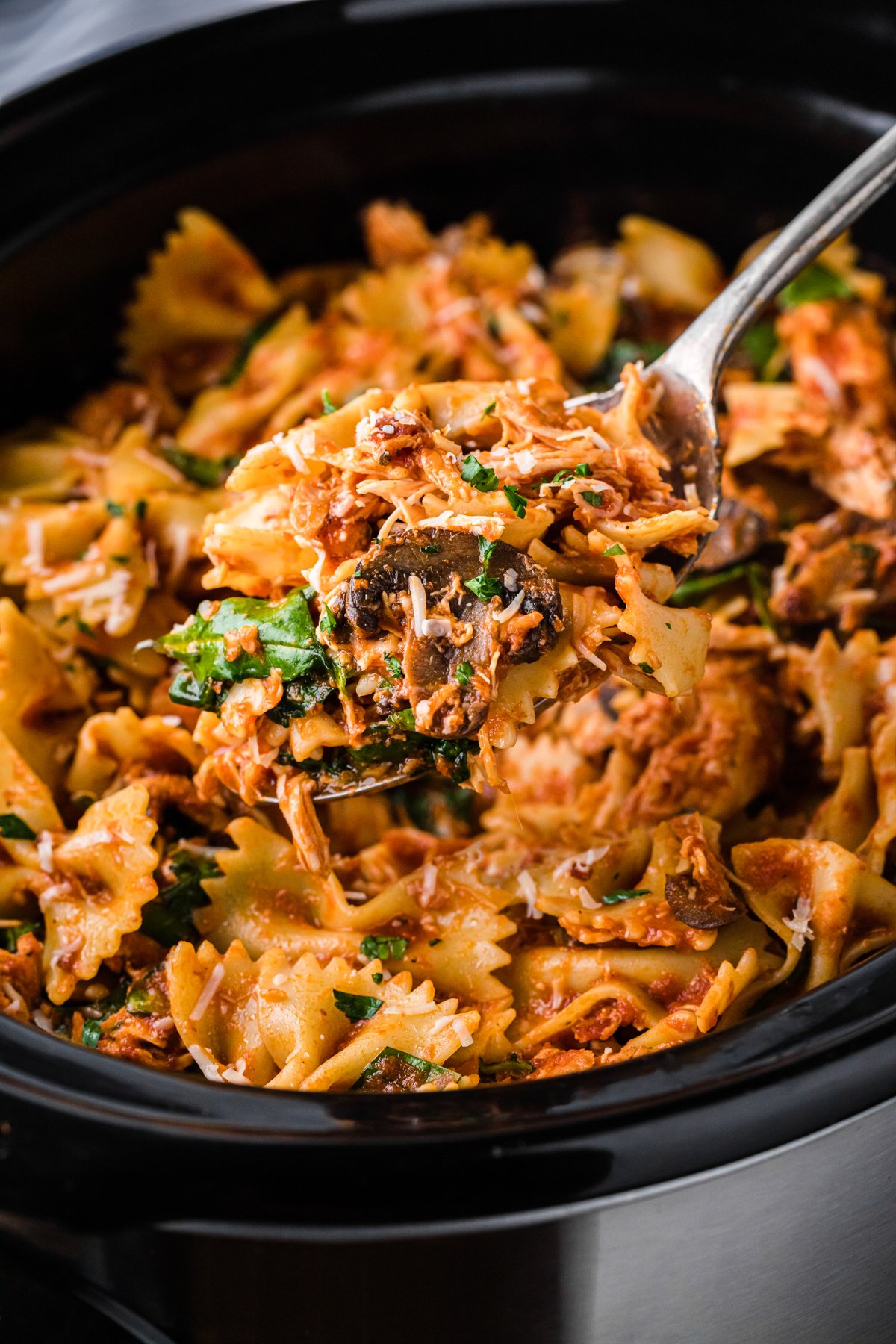 scooping chicken bacon pasta out of a crockpot.