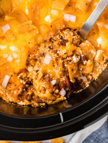 scooping out some chili cheese casserole from a crockpot.