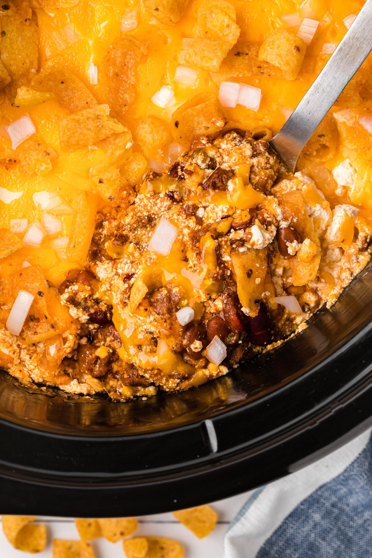 scooping out some chili cheese casserole from a crockpot.