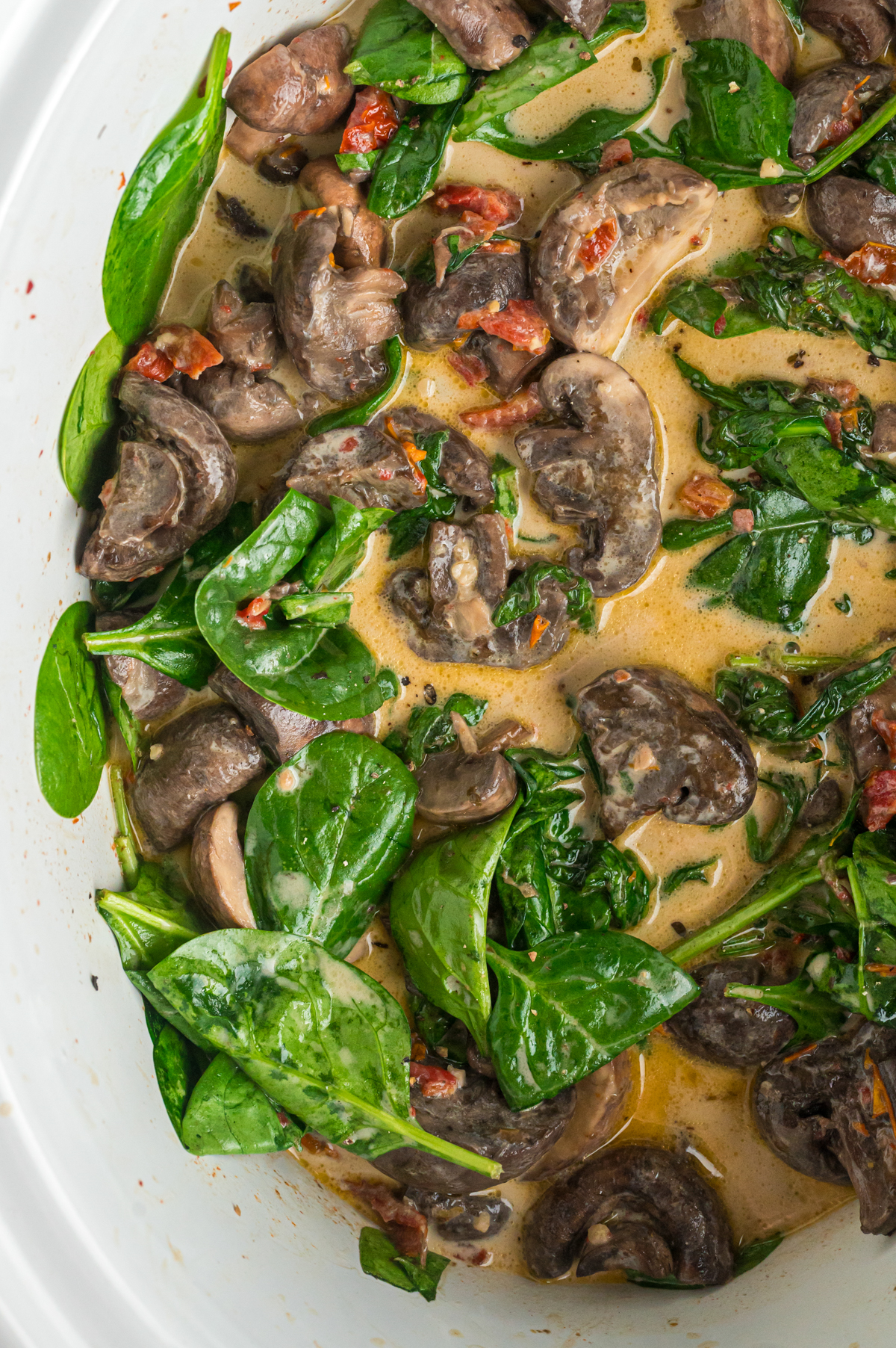 close-up overhead of creamy tuscan mushrooms in crockpot.