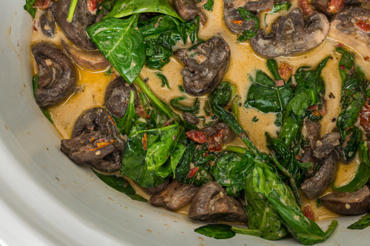 close-up of creamy tuscan mushrooms after cooking in a crockpot.