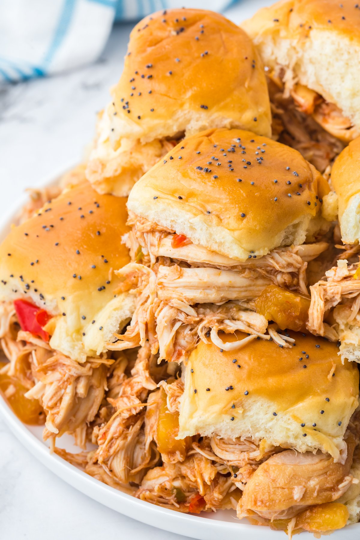 slow cooker Hawaiian sliders stacked on top of each other on a white plate.