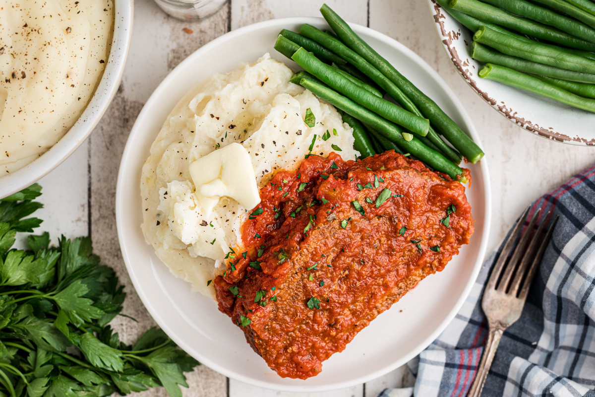 overhead shot of serving of slow cooker Italian meatloaf on a white plate.