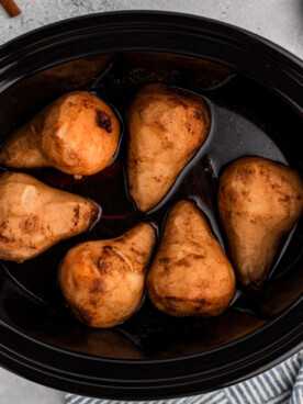 overhead of poached pears in a slow cooker.