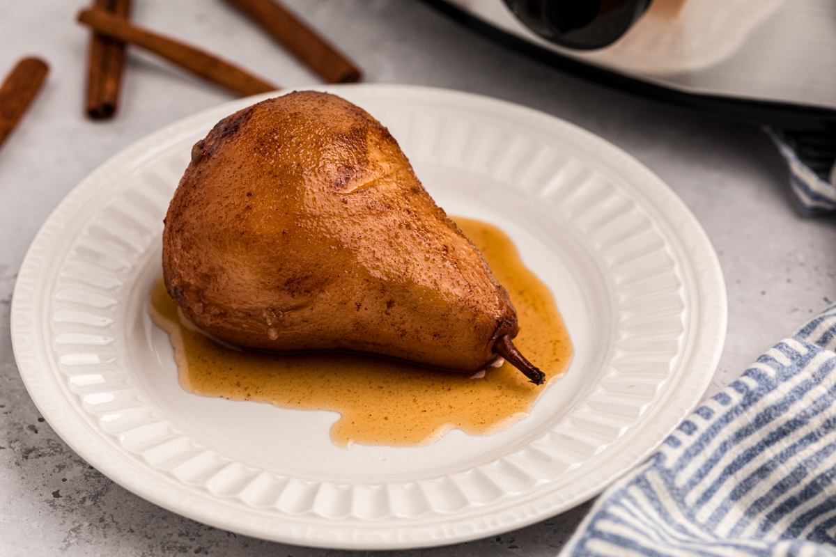 one of the slow cooker poached pears on a white plate.