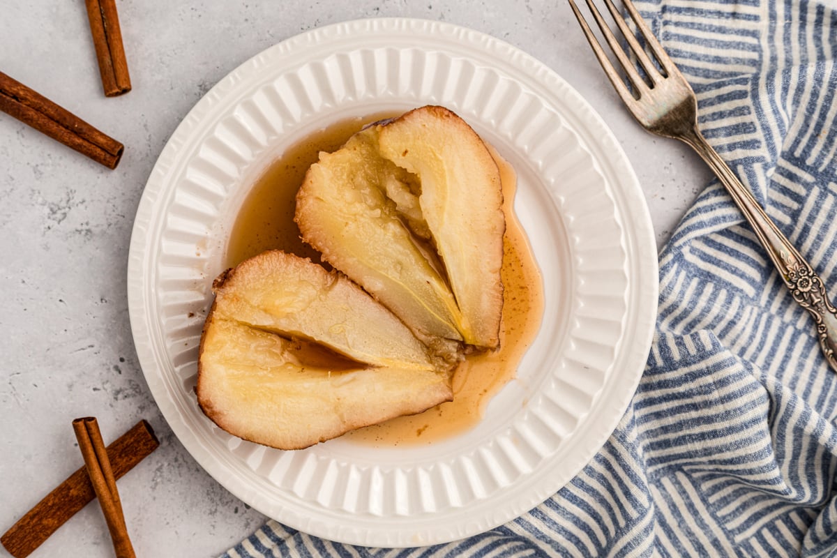 one of the slow cooker poached pears opened up on a white plate.