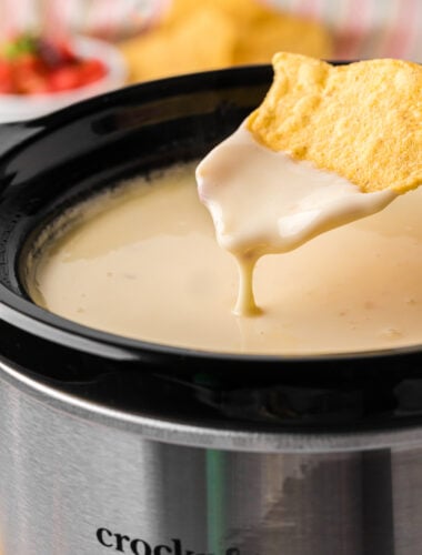 dipping a chip into slow cooker restaurant style queso.