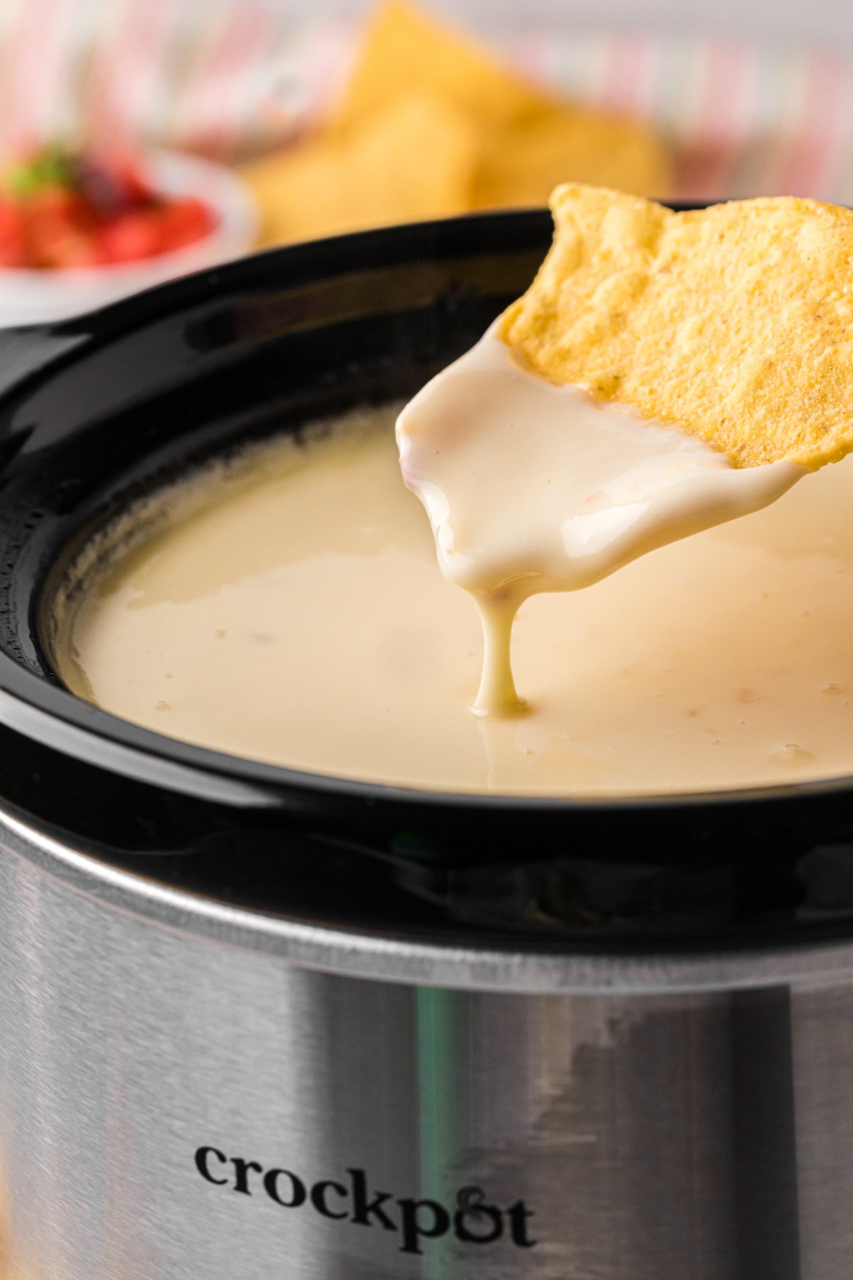 dipping a chip into slow cooker restaurant style queso.