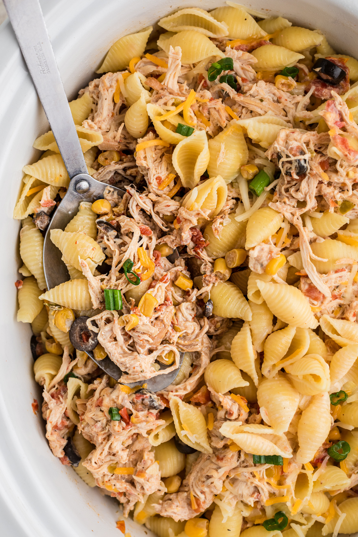 scooping some southwestern cheesy chicken pasta out of a crockpot.