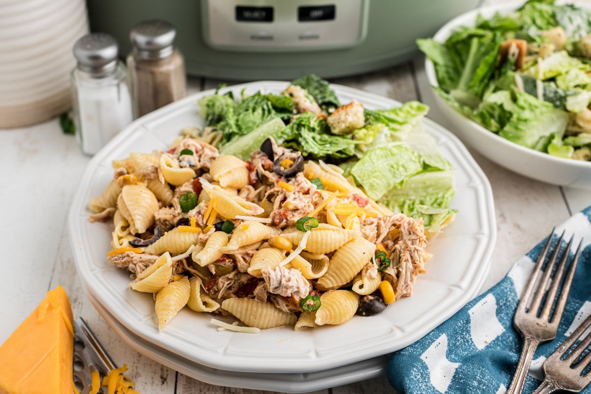 plate of slow cooker southwestern cheesy chicken pasta in front of a crockpot.