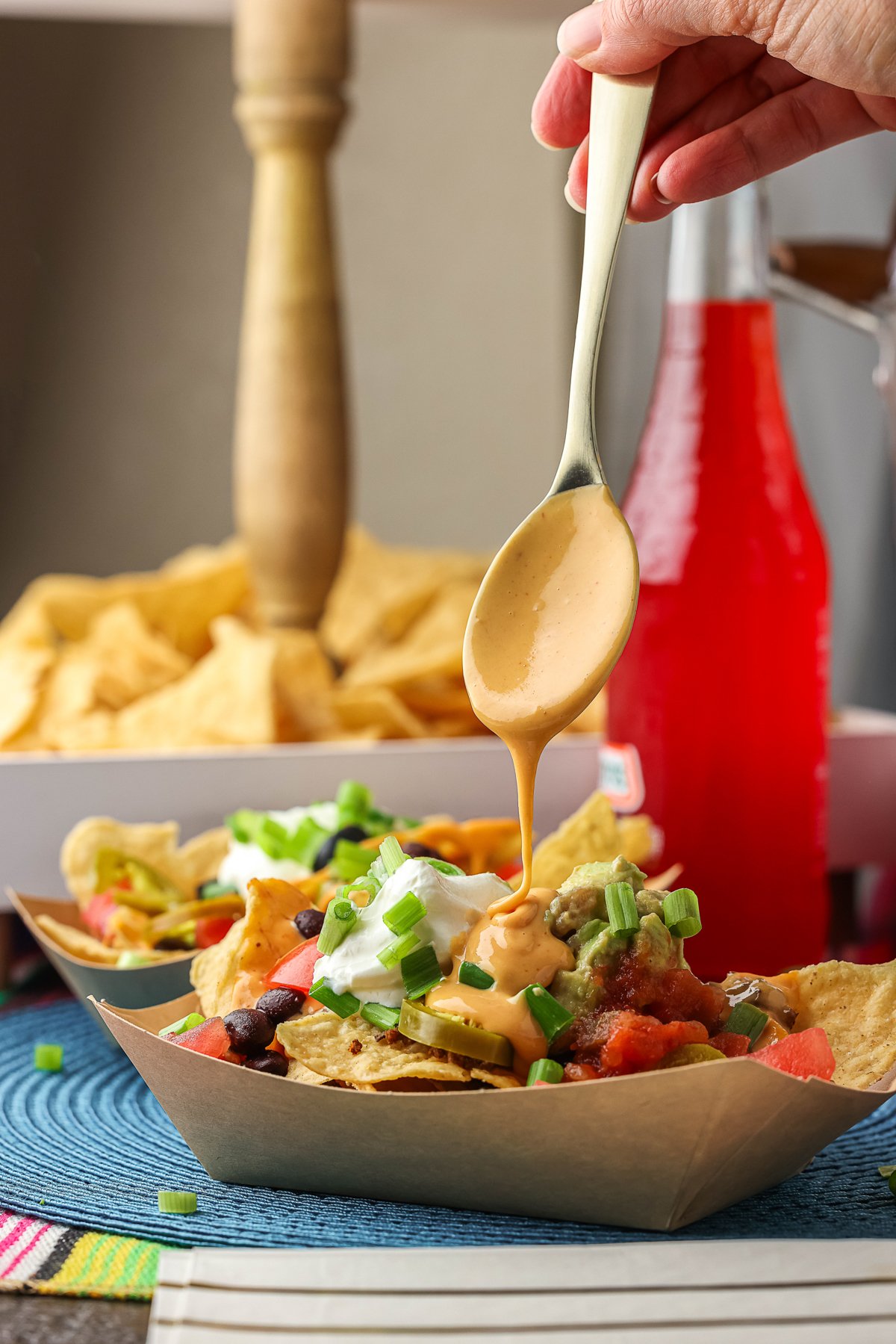 cheese being dripped over nacho chips.