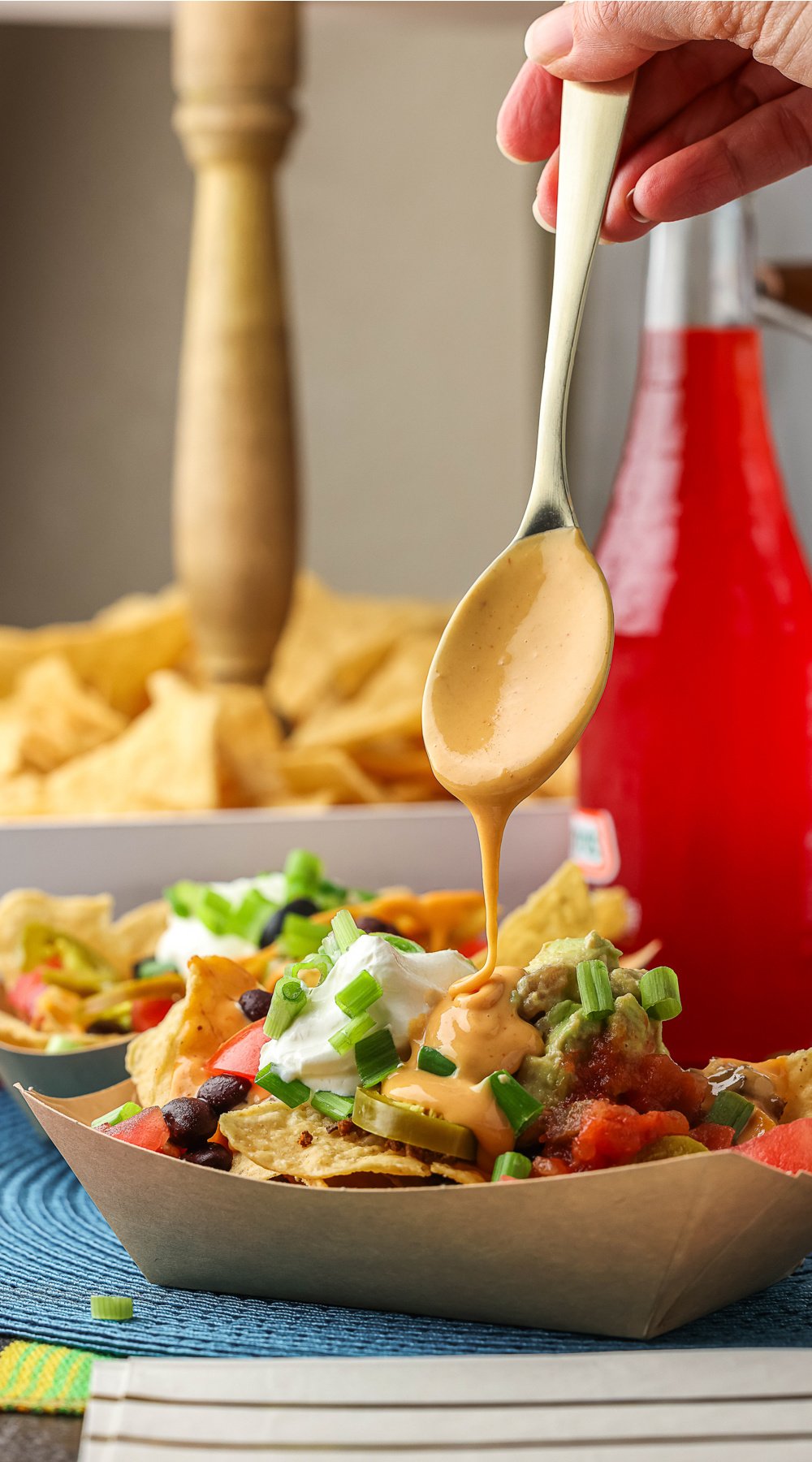 Plate of nachos with nacho cheese drizzling over.